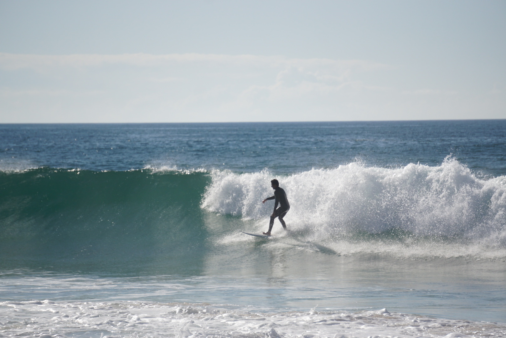 Surfista numa onda em contraluz na Praia Azul, Torres Vedras